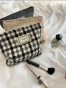 Macro detail of tweed cosmetic bags set with plaid patterns and gold zipper closure