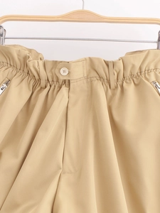 Détail d'un short kaki taille haute avec taille élastique, bouton et fermetures éclair