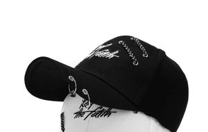 Detail view of cotton baseball cap featuring silver rings, metal chains, and white embroidery