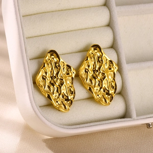 Macro shot of gold stainless steel earrings with artistic irregular lava texture