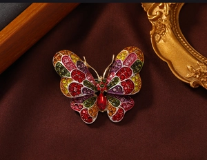 Detail of a vintage butterfly brooch with colorful rhinestones on leather background