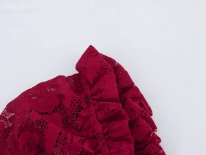 Gros plan sur le tissu en dentelle rouge foncé avec motifs floraux et volants texturés