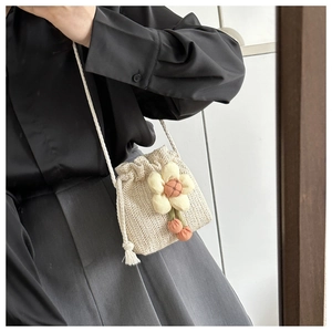 Dettaglio della mini borsa a secchiello in paglia con decoro floreale e coulisse