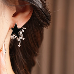 Detail of star-shaped stud earring with tassel drop on model's ear lobe