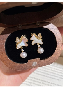 Boucles d'oreilles licorne dorées avec nacre et perles dans un coffret en bois