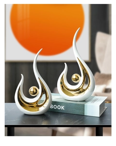 Detail of modern abstract ceramic statues with white finish and gold plating on marble table