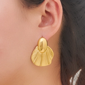 Close-up of elegant gold pleated fan earrings with a polished metallic finish on model