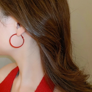 Detailed view of elegant red hoop earrings worn by a model for a chic fashion style