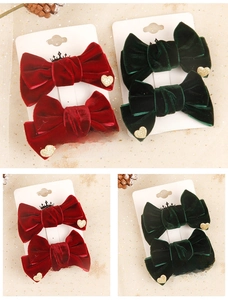 Detail of red and green velvet bow hair clips with gold heart sequins on a display card