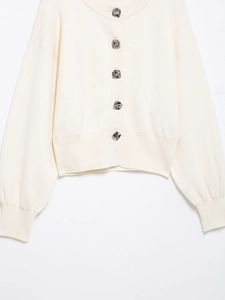Detailed macro view of square embossed silver metal buttons on cream knit cardigan