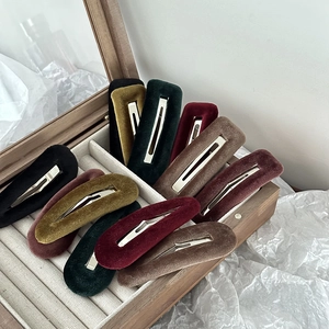 Detailed view of assorted velvet hair clips in drop and rectangle shapes in a wooden box