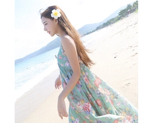 Close-up of green floral maxi dress with vibrant flower patterns at a sunny beach