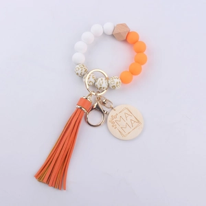 Detail view of MAMA silicone bead keychain with orange tassels and leopard print beads