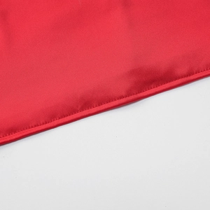 Macro shot of red satin fabric edge with precise flat stitching on summer dress