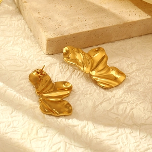 Golden irregular pleated flower stud earrings in stainless steel on a textured background