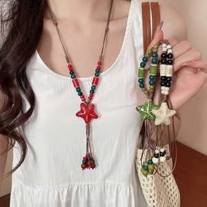 Detail view of handmade ceramic starfish pendant and colorful beads on woven cord