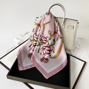 Floral pink satin silk scarf with belt patterns elegantly draped over white leather handbag