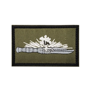 Detailed embroidery of an olive tactical patch featuring a white dagger and ray pattern