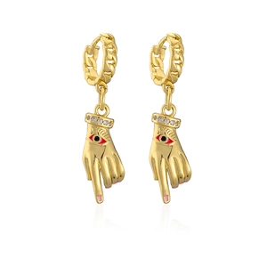 Detail of gold-plated hand-shaped earrings with red eye design and crystal wrist