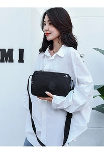 Nylon crossbody bag shown on a female model wearing a white shirt against a white wall