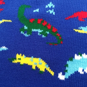Close-up of jacquard knit fabric showing colorful dinosaur patterns and texture