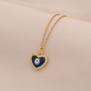 Dettaglio del ciondolo a cuore dorato con occhio blu e strass lucenti su collana