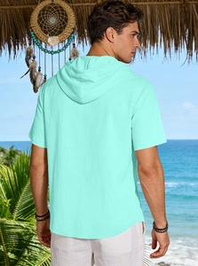 Back view of men's linen hooded shirt in mint green against a tropical beach resort