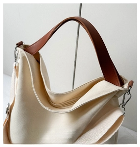 Detail view of large canvas tote bag with brown leather handles and silver ring hardware