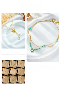 Detail of layered gold necklaces with butterfly, heart pendants and pearl accents