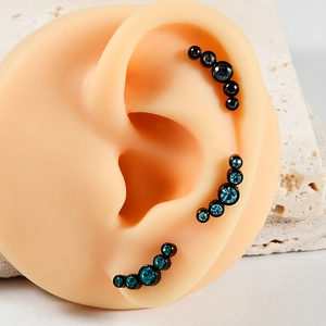 Detailed close-up of curved curved surgical steel ear studs with five inlaid opal stones