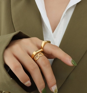 Detail of stacked irregular geometric gold rings on model wearing dark green suit