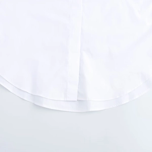 Detailed macro view of the curved hem and fabric texture of a white long sleeve shirt