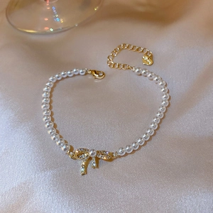 Bracelet en perles baroques avec breloque nœud doré étincelant sur fond en soie rose