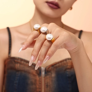 Luxurious 18K gold plated titanium rings with large pearls worn on female model's hand