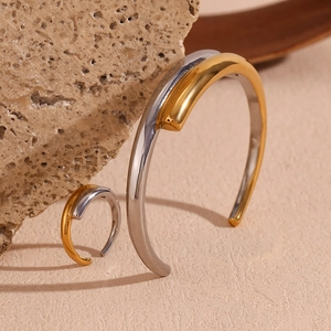 Detail of minimalist two-tone intertwined bangle and ring set with golden accents