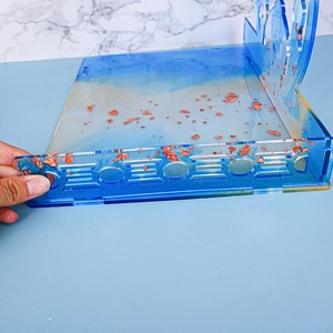 Close-up of translucent blue resin tray with gold foil flakes and laser-cut details