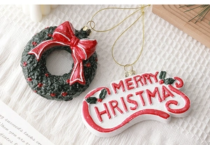 Close-up of resin Christmas wreath and Merry Christmas letter pendants on white knit texture