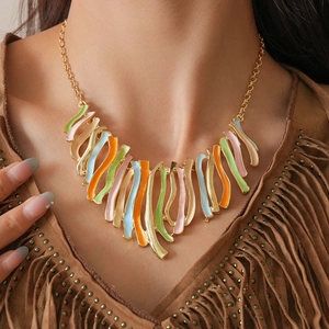 Détail d'un collier bohème avec pendentifs en émail coloré et chaîne dorée sur mannequin