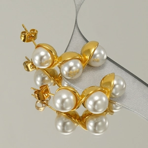Elegant gold pearl pea earrings on grey mirror surface with ribbon decoration