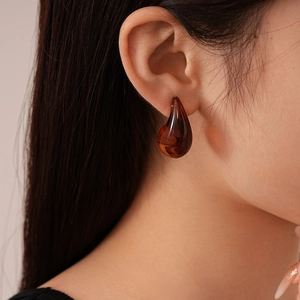Gros plan sur les boucles d'oreilles en résine ambre avec texture marbrée rétro