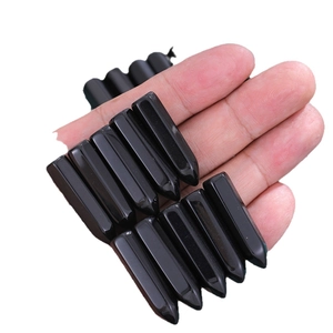 Set of ten polished black obsidian hexagonal column pendants held in hand on white background