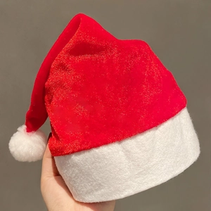 Classic red sequin Christmas hat with white plush trim and pompom held by hand