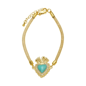 Detalle de pulsera de malla dorada con colgante de corazón turquesa y circonitas blancas