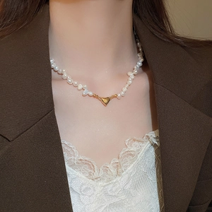 Close-up of irregular freshwater pearl necklace with 18K gold heart pendant on model