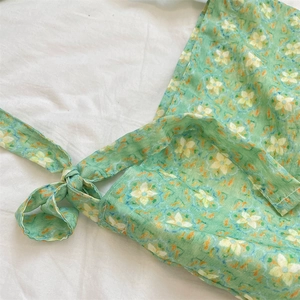 Macro detail of green floral print tote bag showing fabric texture and bow tie strap