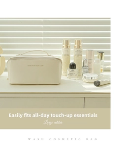 Close-up of large caliber cream leather toiletry bag with gold lettering and top handle