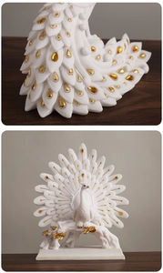 Close-up detail of white resin peacock statue with gold accents and crystal inlaying