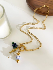 Detail of 18K gold clip chain necklace with blueberry pendant and pearl accents