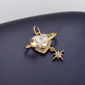 Macro shot of gold-plated heart planet pendant with zircon stones and star drop