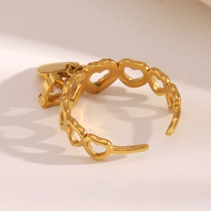 Detailed close-up of 18K gold-plated open ring with heart cutout and dangling charm